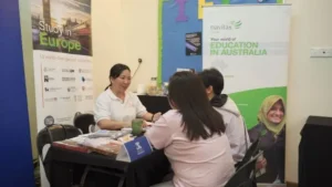 Education consultation booth with Navitas banner promoting Australian education opportunities and representative meeting with prospective students